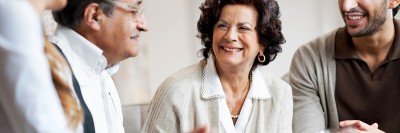 Photo of four people around a table smiling and conversing.