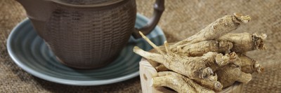 A bowl of ginseng root sitting next to a teapot.