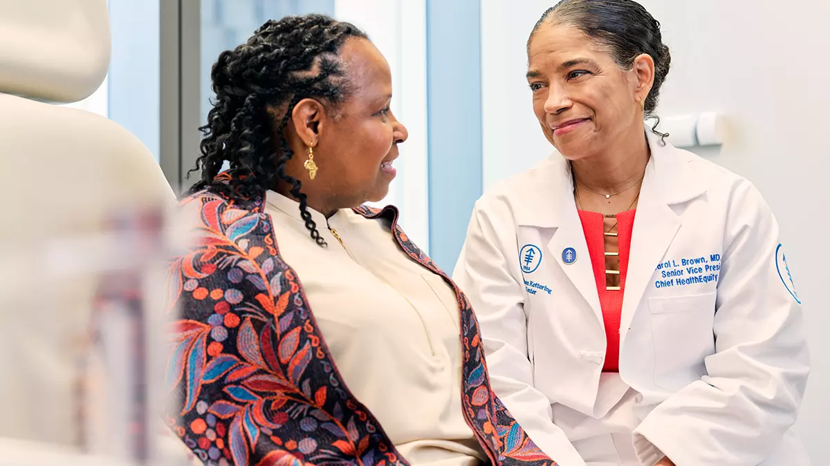Gynecologic surgeon Carol Brown shares a warm and engaged conversation with MSK patient Linda Collins in a medical office.